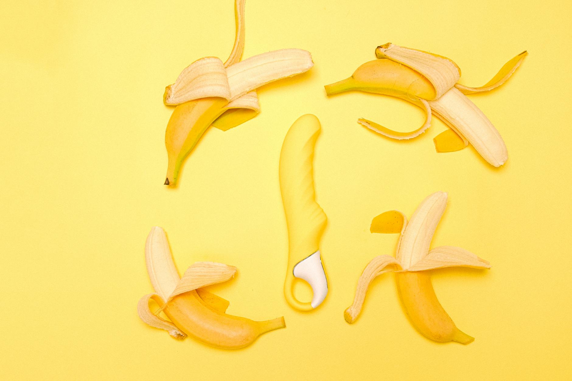 Yellow lemon-shaped clitoral suction toy surrounded by fresh lemons and peeled segments on bright yellow background