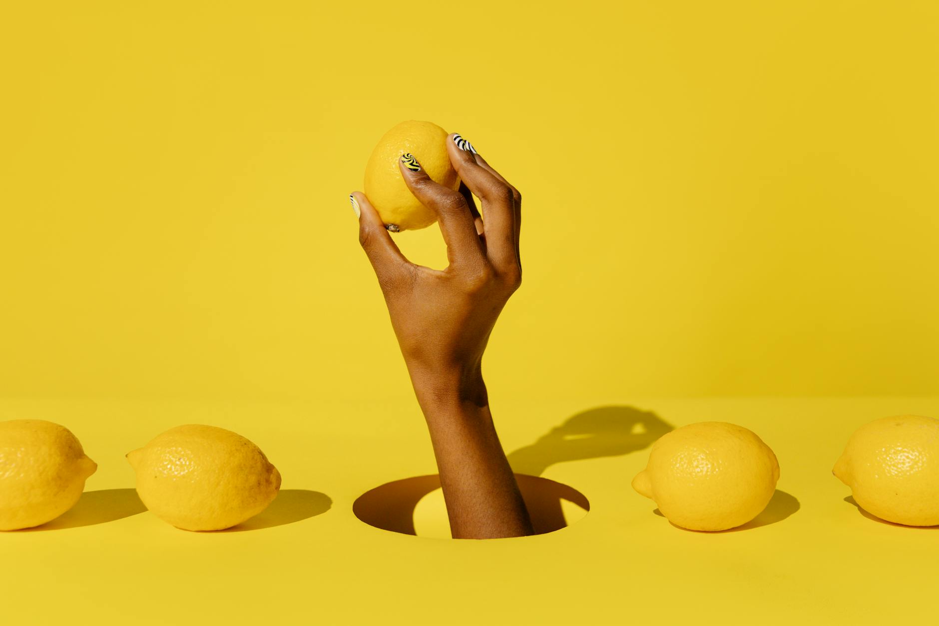 A hand holding a fresh lemon against a bright yellow background, representing the delicate and gradual intensity of pleasure