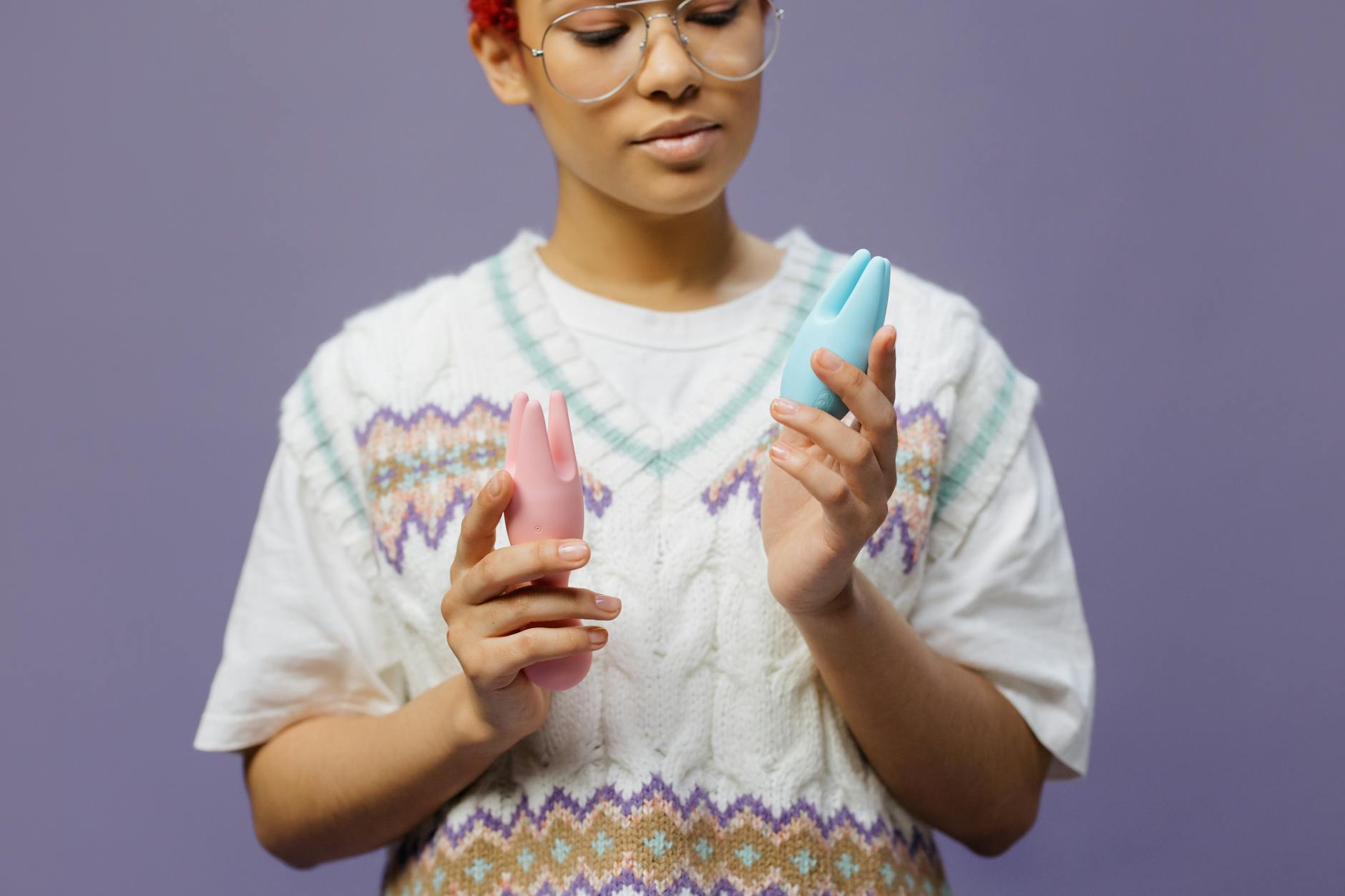 Woman contemplating two vibrators, exploring pleasure intentionally